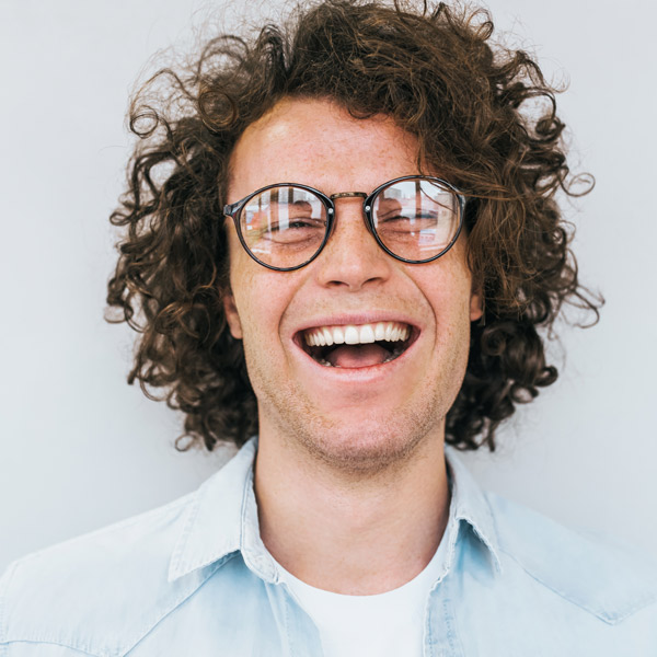 man with curly hair and glasses laughing
